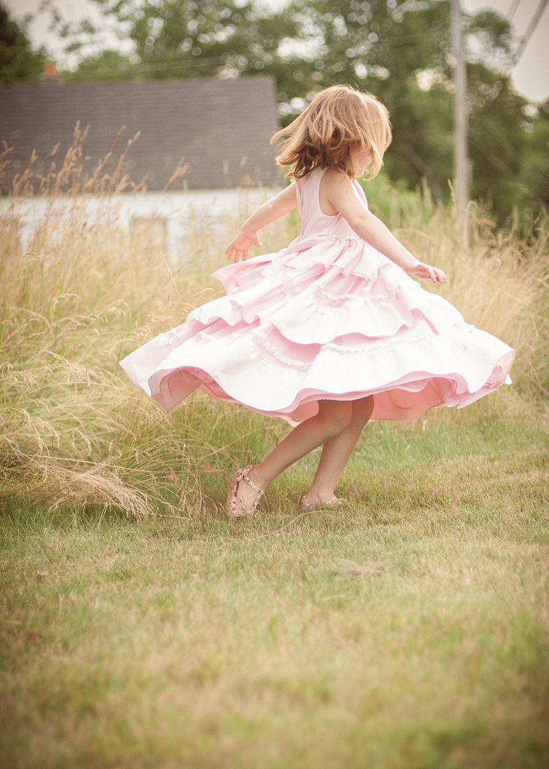 Girl twirling pink dress in a country field